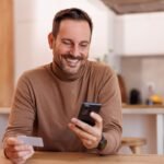 Comment Contacter Fortuneo en Tant que Nouveau Client client-souriant-utilisant-smartphone-contact-fortuneo