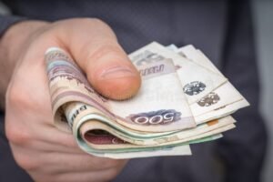 pile de billets avec mains echangeant confidentialement